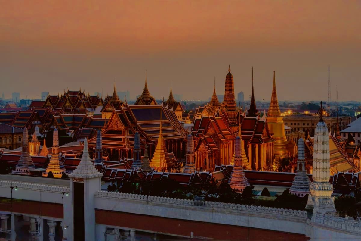 Best of Bangkok and Pattaya Grand Palace Bangkok with illuminated golden stupas and red-roofed temples at dusk, Thailand skyline in background
