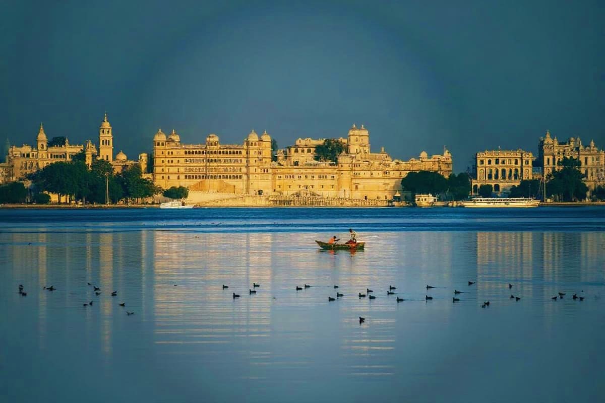 Historic palace architecture on Lake Pichola in Udaipur, Rajasthan with traditional boat and waterfowl