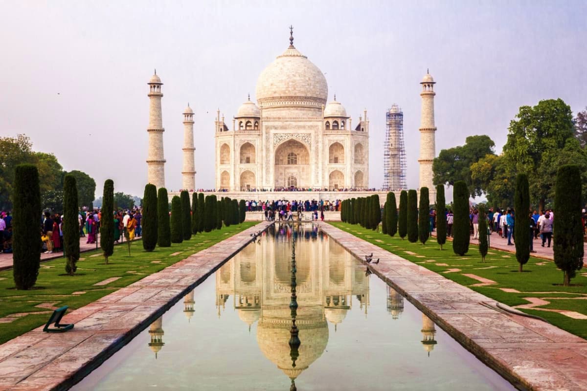Taj Mahal with reflecting pool, cypress trees, and tourists in Agra, India