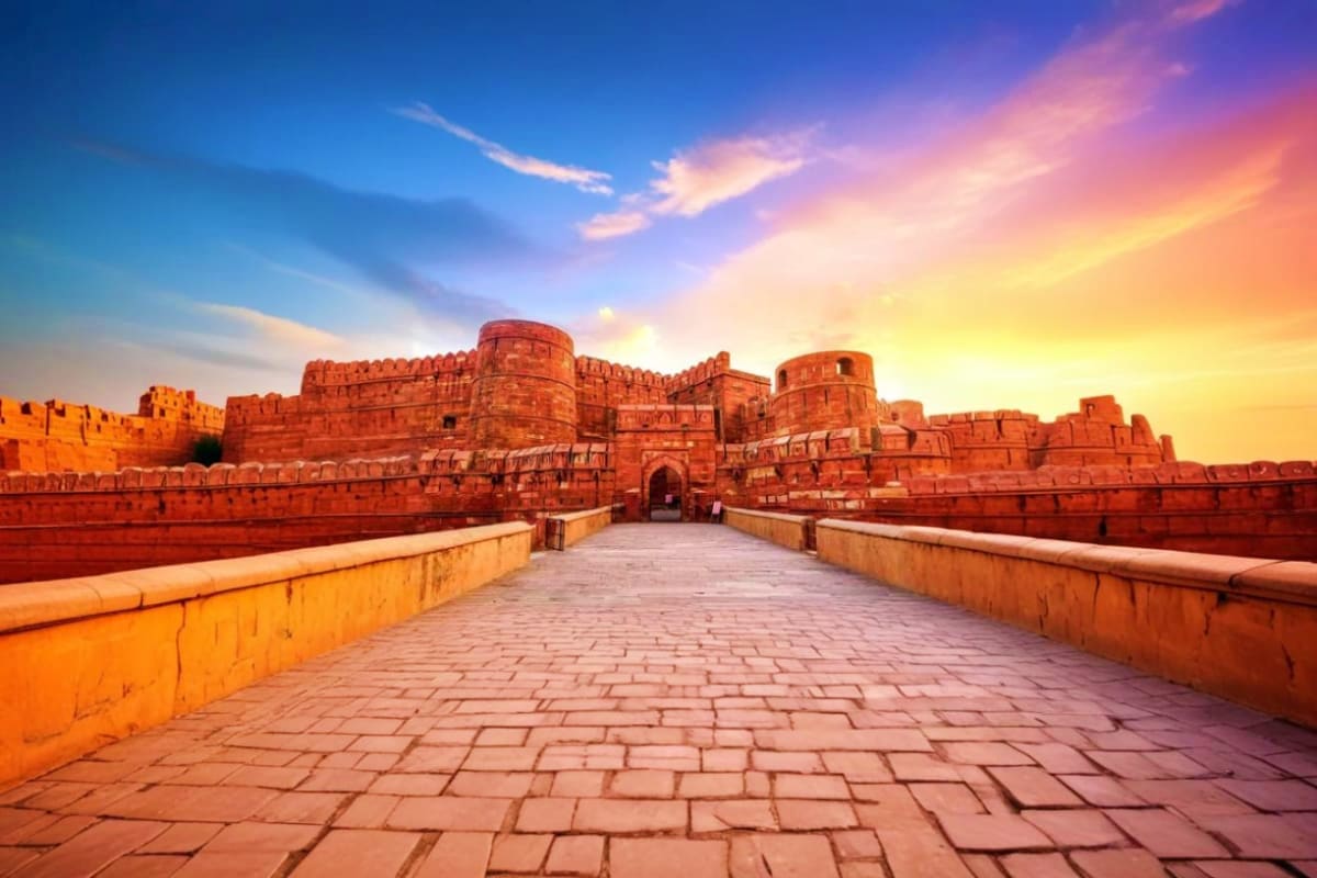 Agra Fort's red sandstone walls and gateway at sunset during golden hour in Agra, India