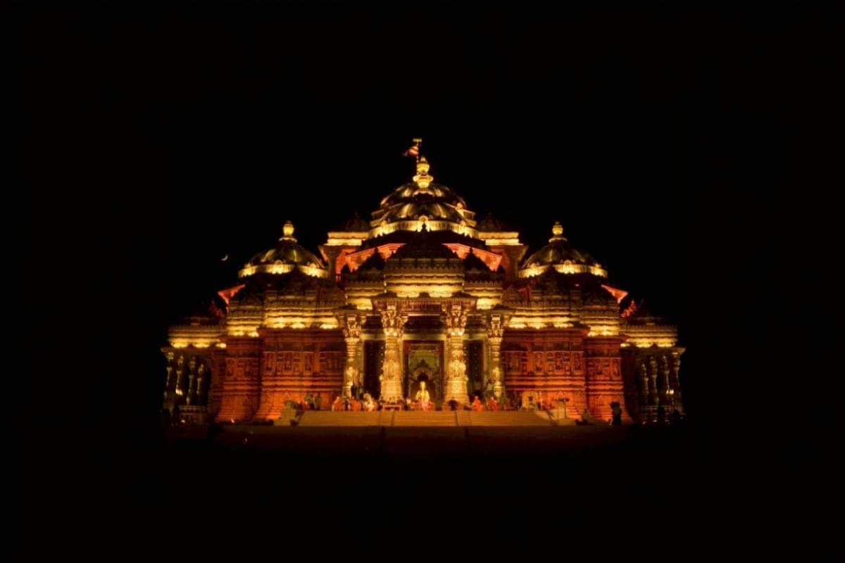 Akshardham Temple illuminated at night with golden and warm lighting against dark sky in New Delhi, India