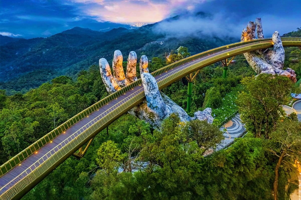 Giant stone hands supporting a golden bridge spanning mountainous jungle landscape in Vietnam