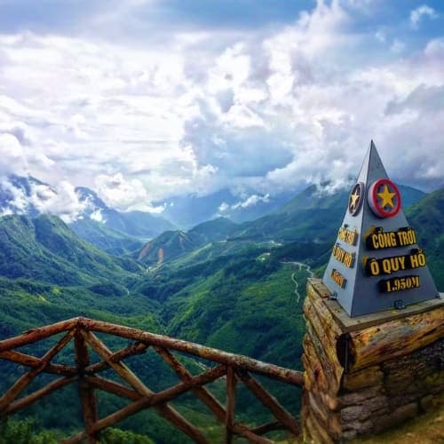O Quy Ho mountain pass summit marker with dramatic valley landscape and snow-capped peaks in Vietnamese highlands
