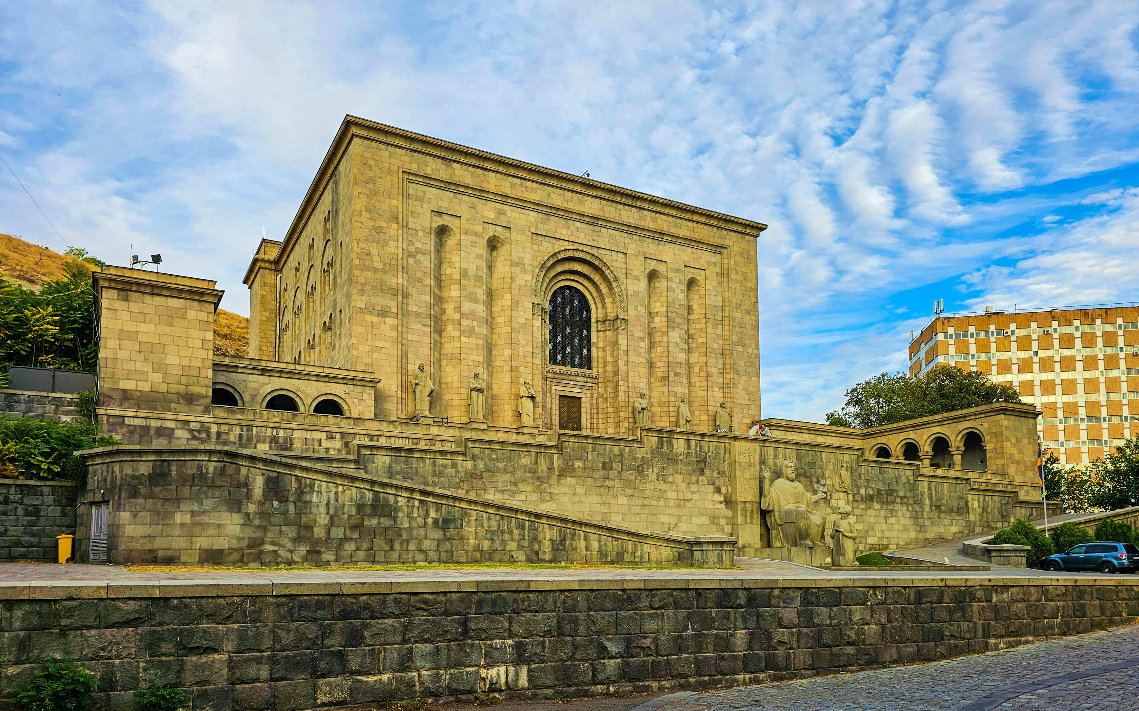 Armenia Historic stone building with arched windows and decorative facade in Armenia, surrounded by modern apartment buildings under