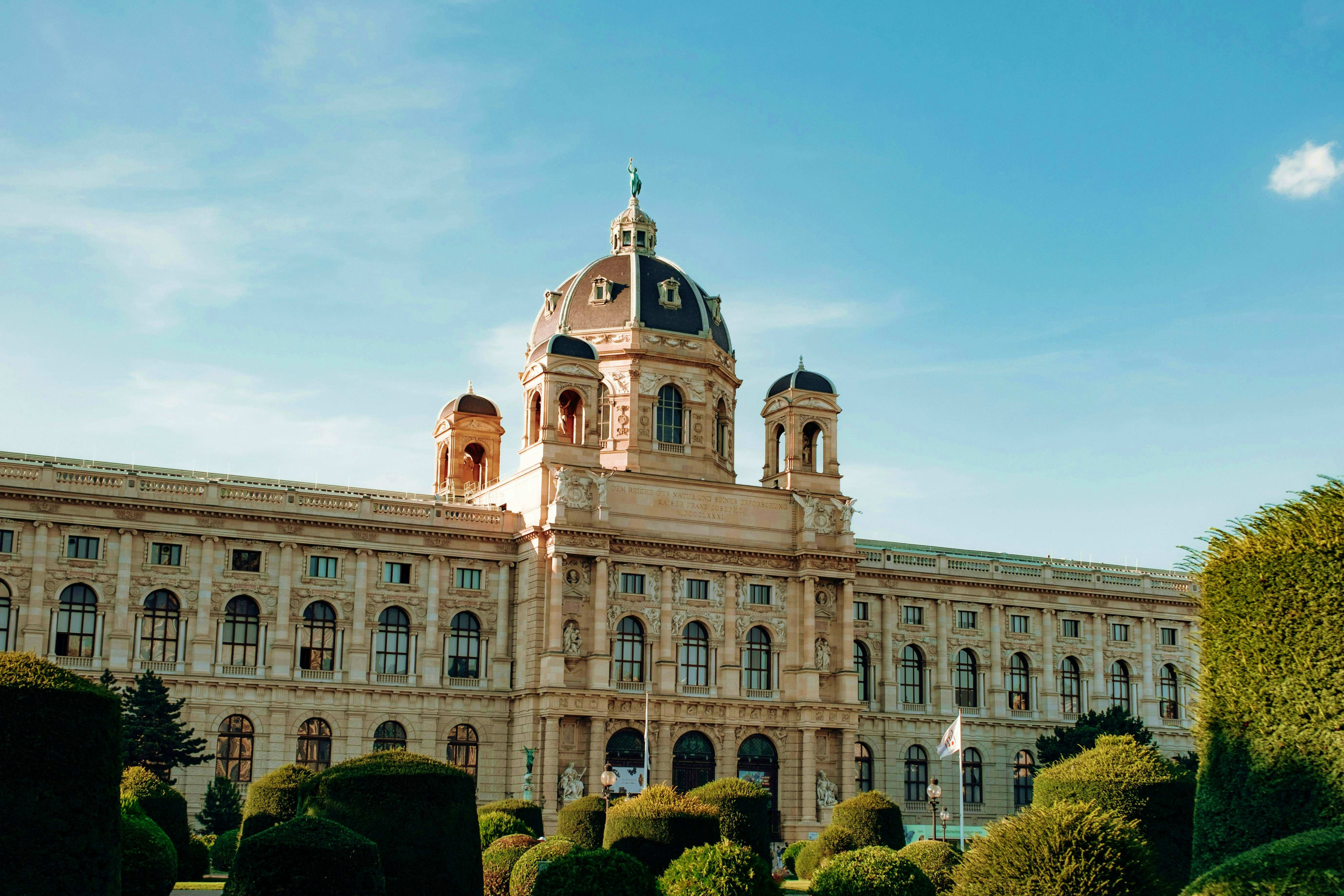 Austria Natural History Museum Vienna with ornate dome and manicured gardens under blue sky