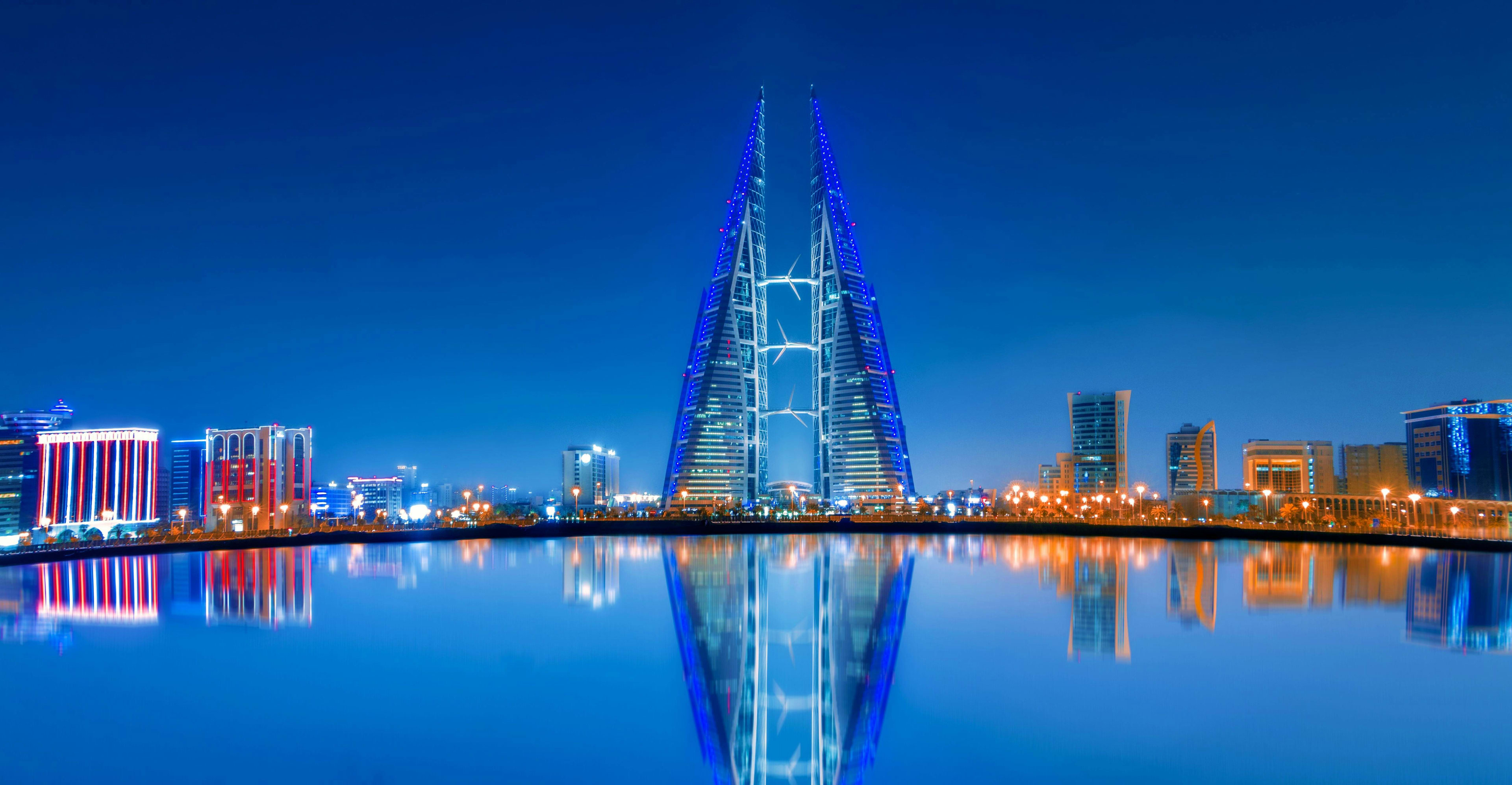 Bahrain Bahrain skyline at dusk with illuminated Bahrain World Trade Center twin towers reflected in still water