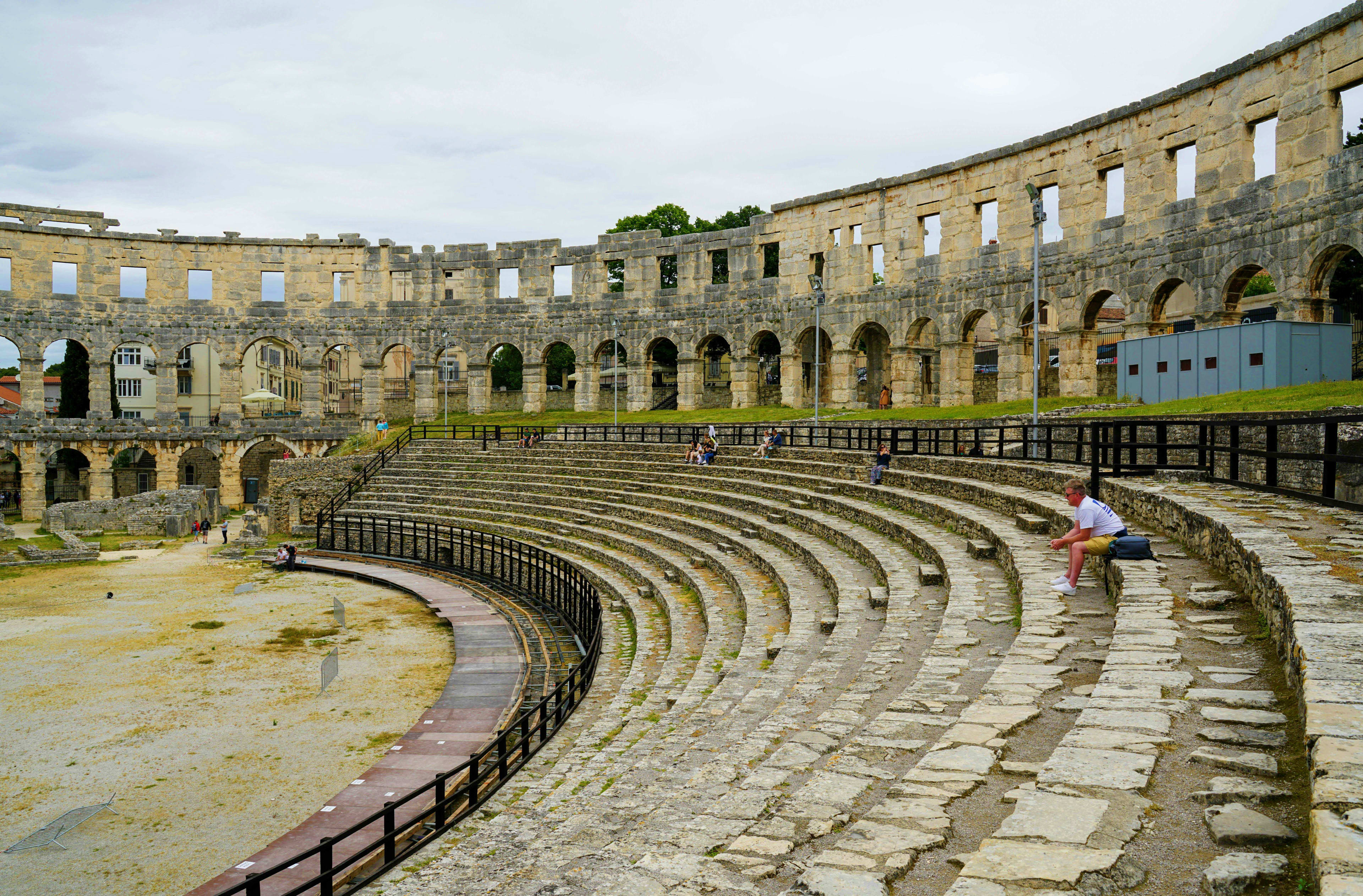 Croatia Roman amphitheater ruins in Pula, Croatia with stone arches and seating tiers surrounded by ancient walls