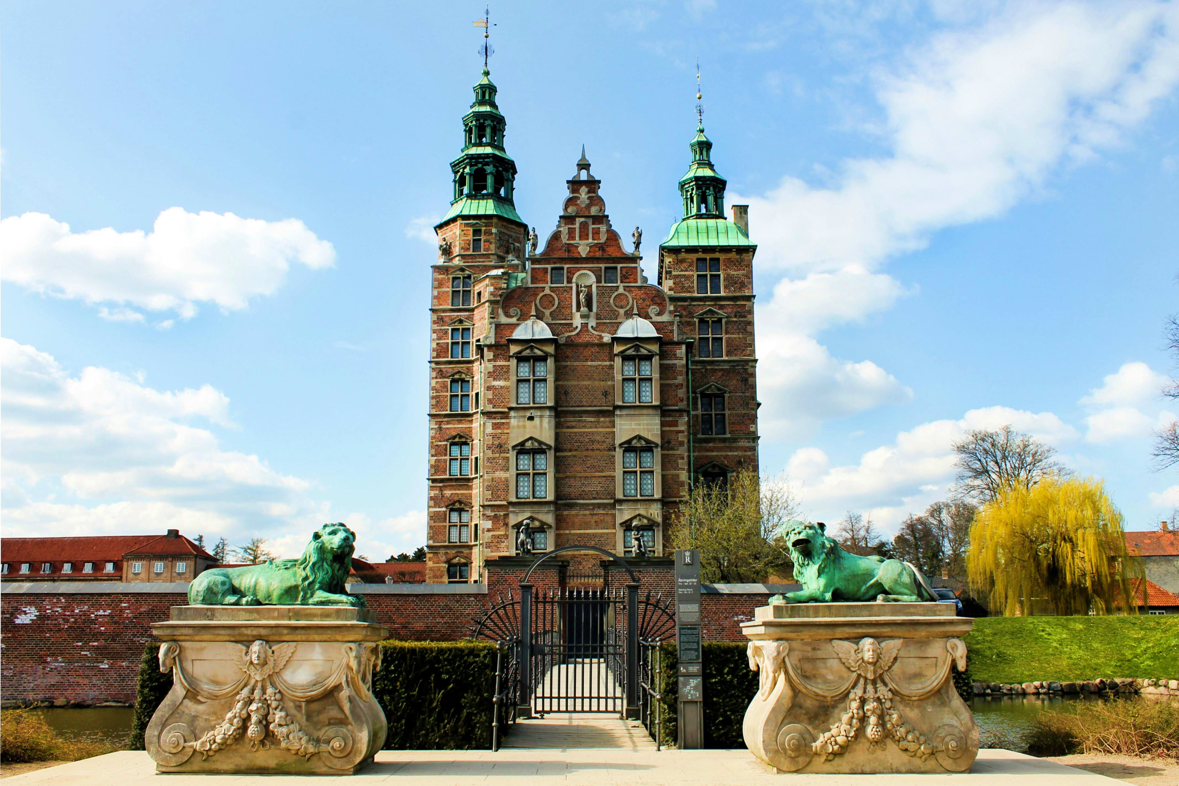 Denmark Rosenborg Castle in Copenhagen, Denmark, with green copper spires and oxidized lion statues guarding the entrance gate
