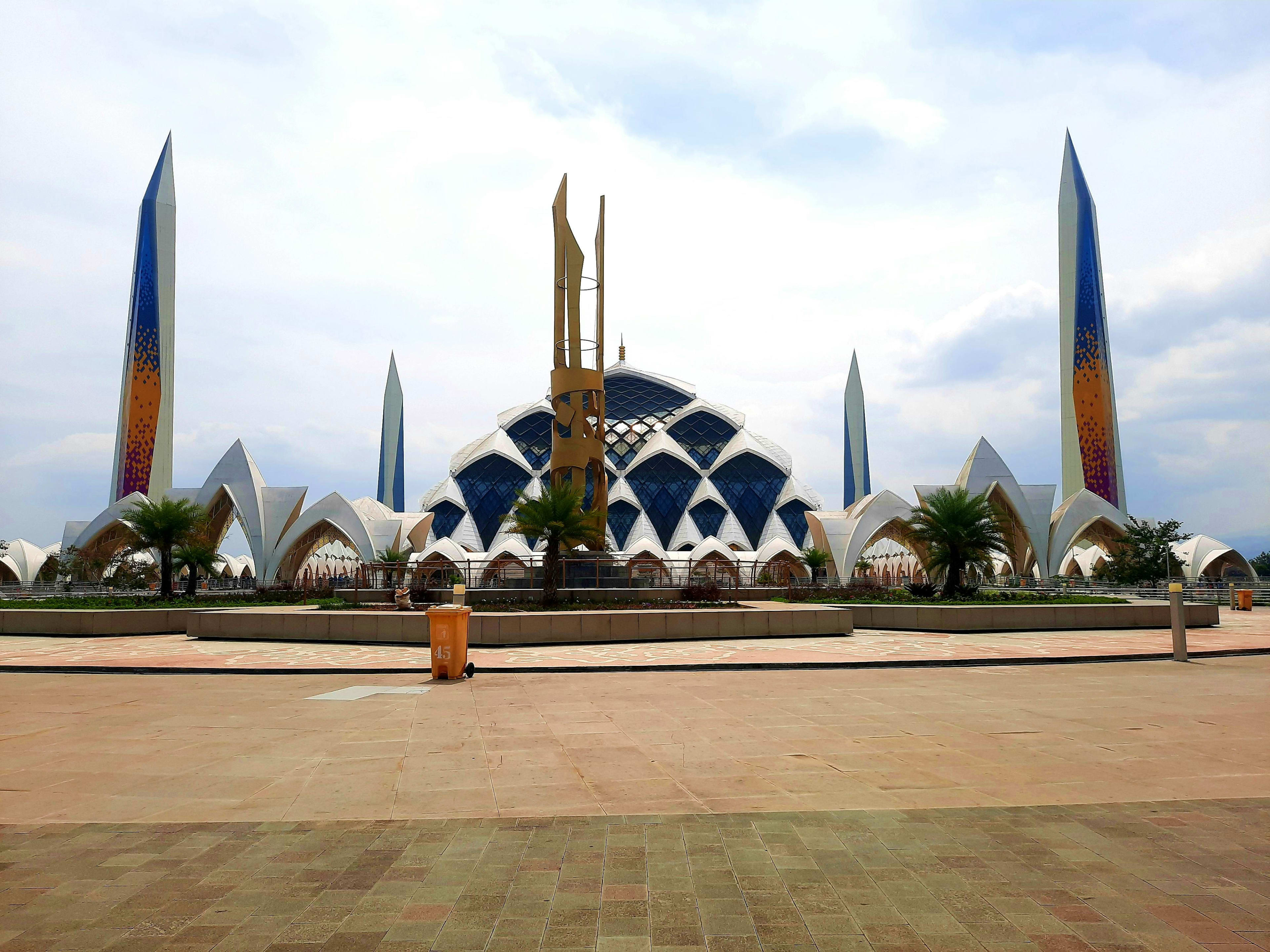 Indonesia Modern white architectural complex with ornate spires and solar panels in Indonesia, surrounded by palm trees and paved plaza