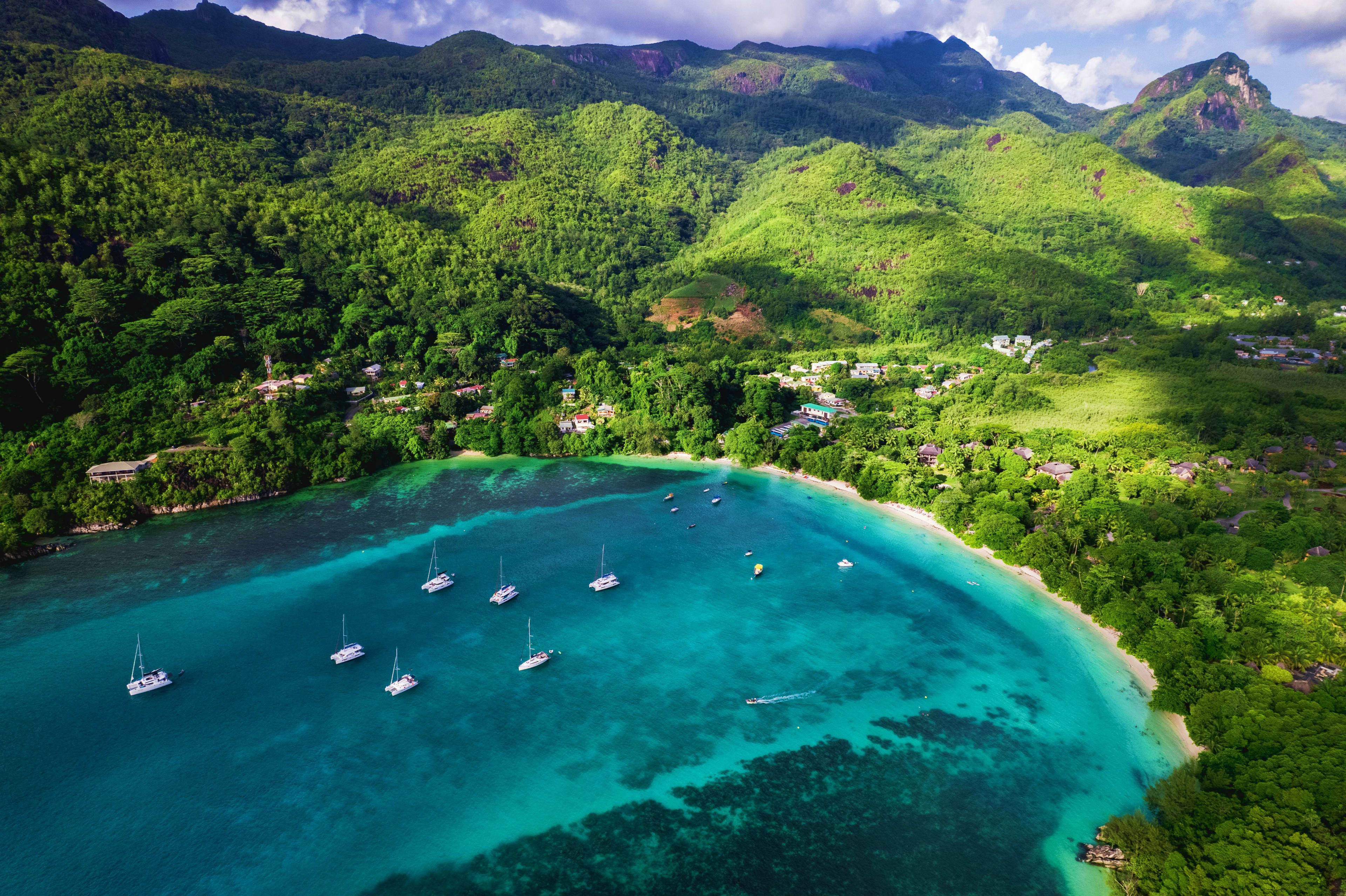 Seychelles Aerial view of a turquoise bay with sailboats, white sand beach, and lush forested mountains in Seychelles