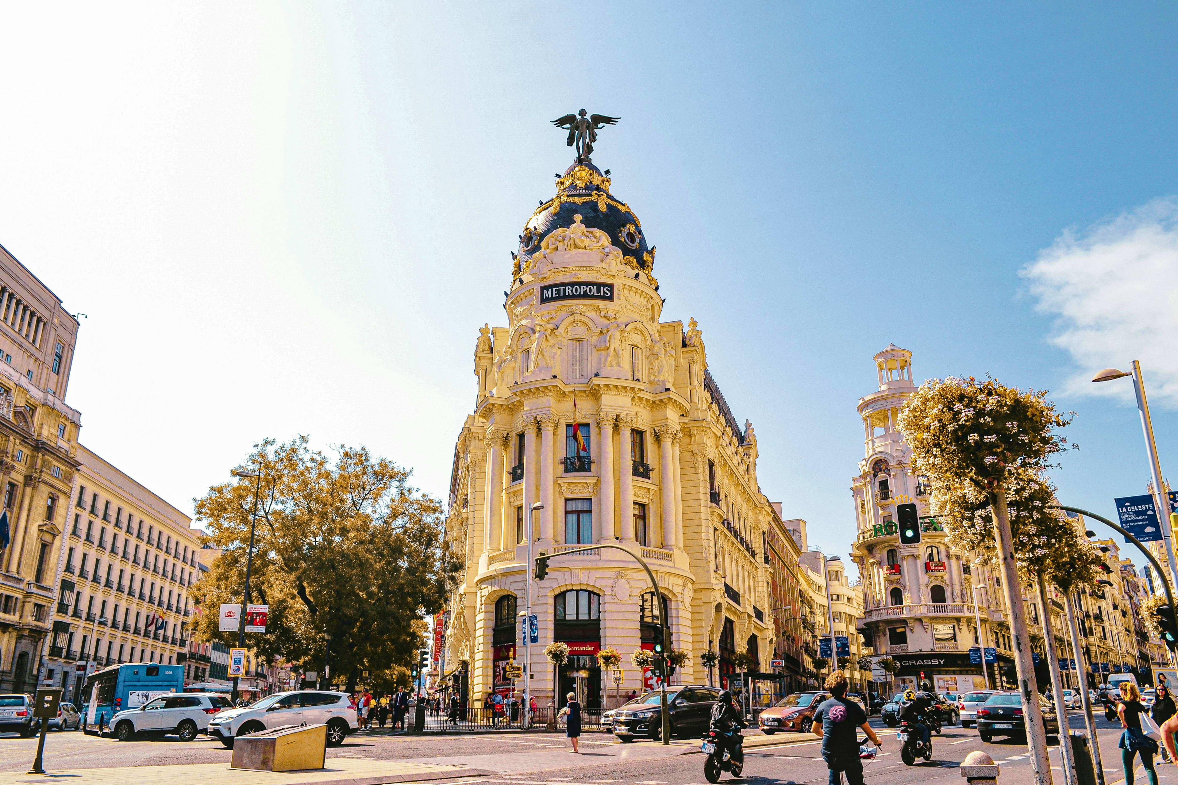 Spain Metropolis Building in Madrid, Spain, a yellow ornate early 20th century landmark with a winged statue on top, surrounded by