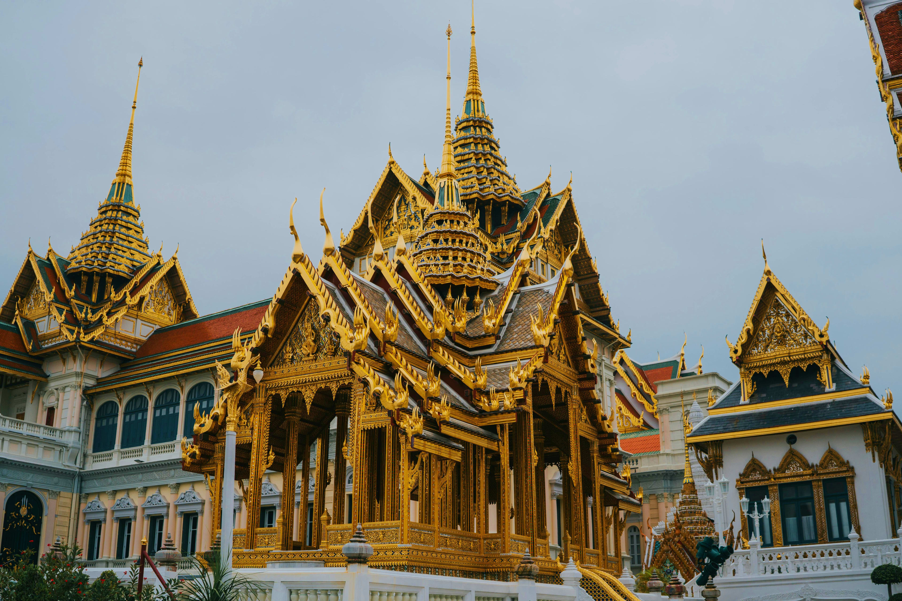 Thailand Grand Palace Bangkok with ornate golden spires, tiered roofs, and intricate Thai temple architecture under blue sky