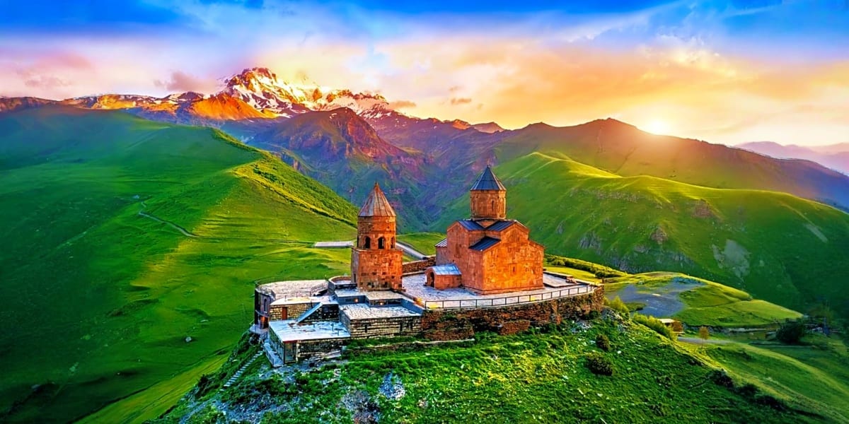 Tatev Monastery nestled in green valleys with snow-capped mountain peaks at sunrise in Armenia
