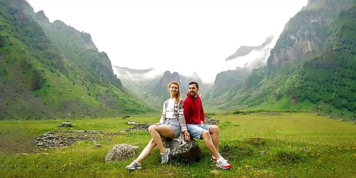 Couple sitting on a rock in a lush green mountain valley with steep forested peaks and mist in Appalachian landscape