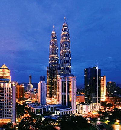 Petronas Twin Towers illuminated at dusk in Kuala Lumpur skyline with surrounding buildings and cityscape