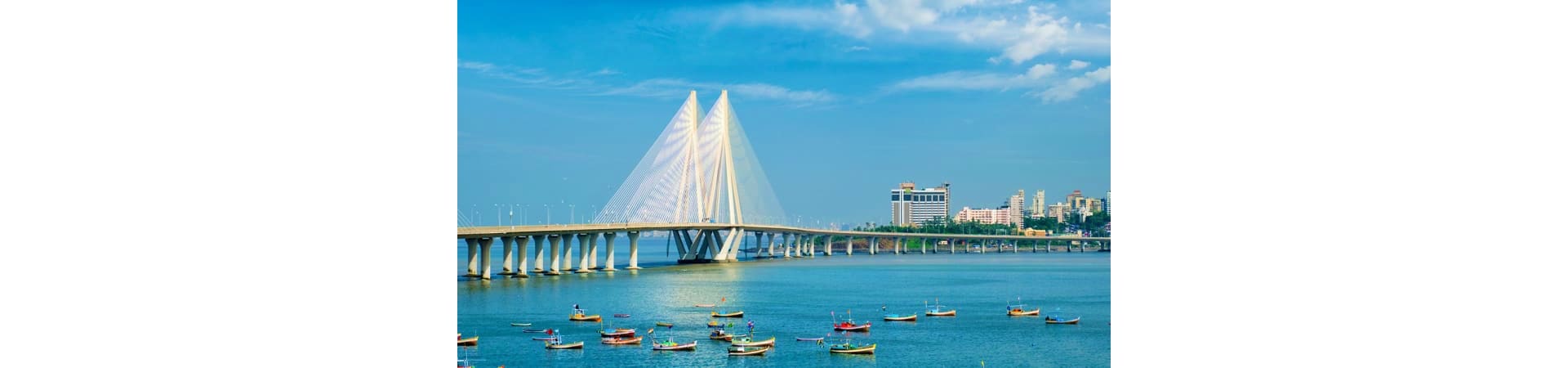 Bandra-Worli Sea Link cable-stayed bridge spanning blue Arabian Sea waters with Mumbai skyline and boats in foreground