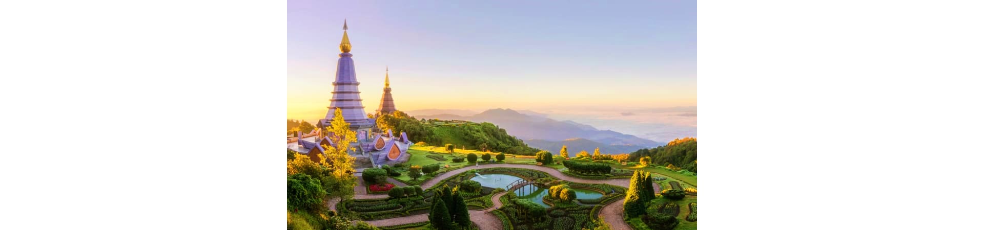 Doi Inthanon temple with golden spires at sunrise overlooking manicured gardens and mountain landscape in Chiang Mai, Thailan