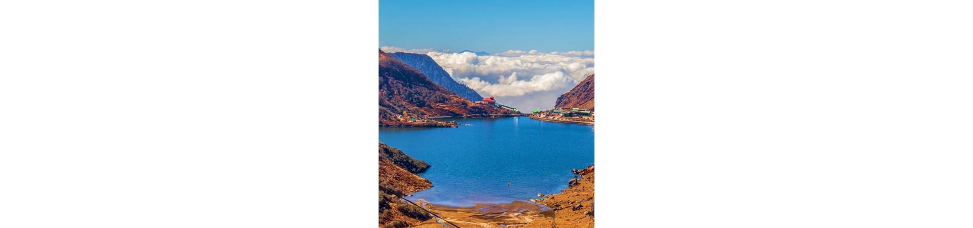 Mountain lake surrounded by rocky peaks with white clouds above, Gangtok region landscape