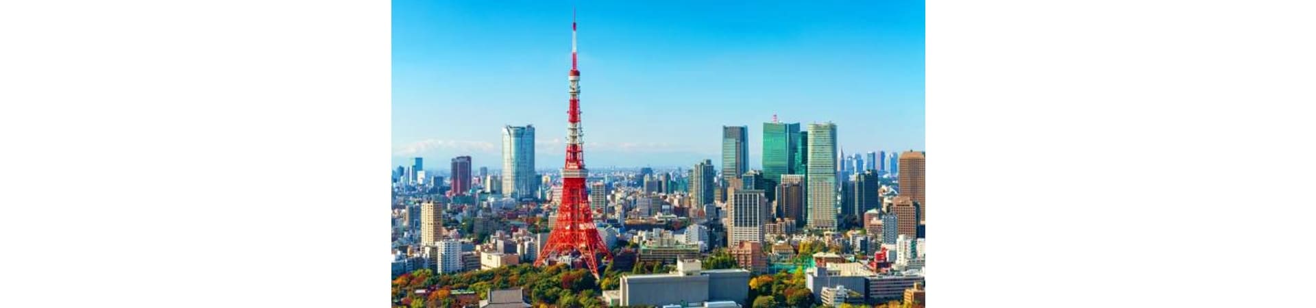 Tokyo skyline with red Tokyo Tower landmark surrounded by modern skyscrapers and clear blue sky