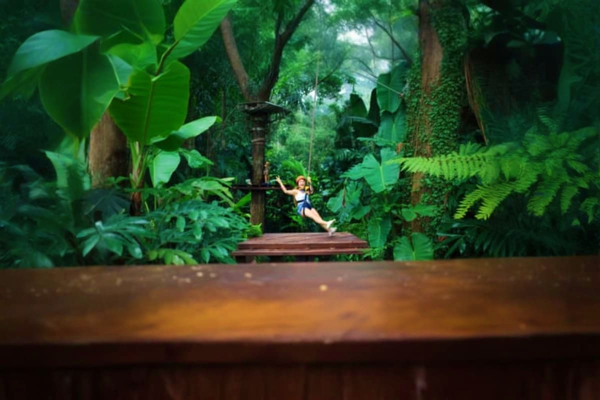 Woman on zip line through dense jungle canopy at Hanuman World adventure park