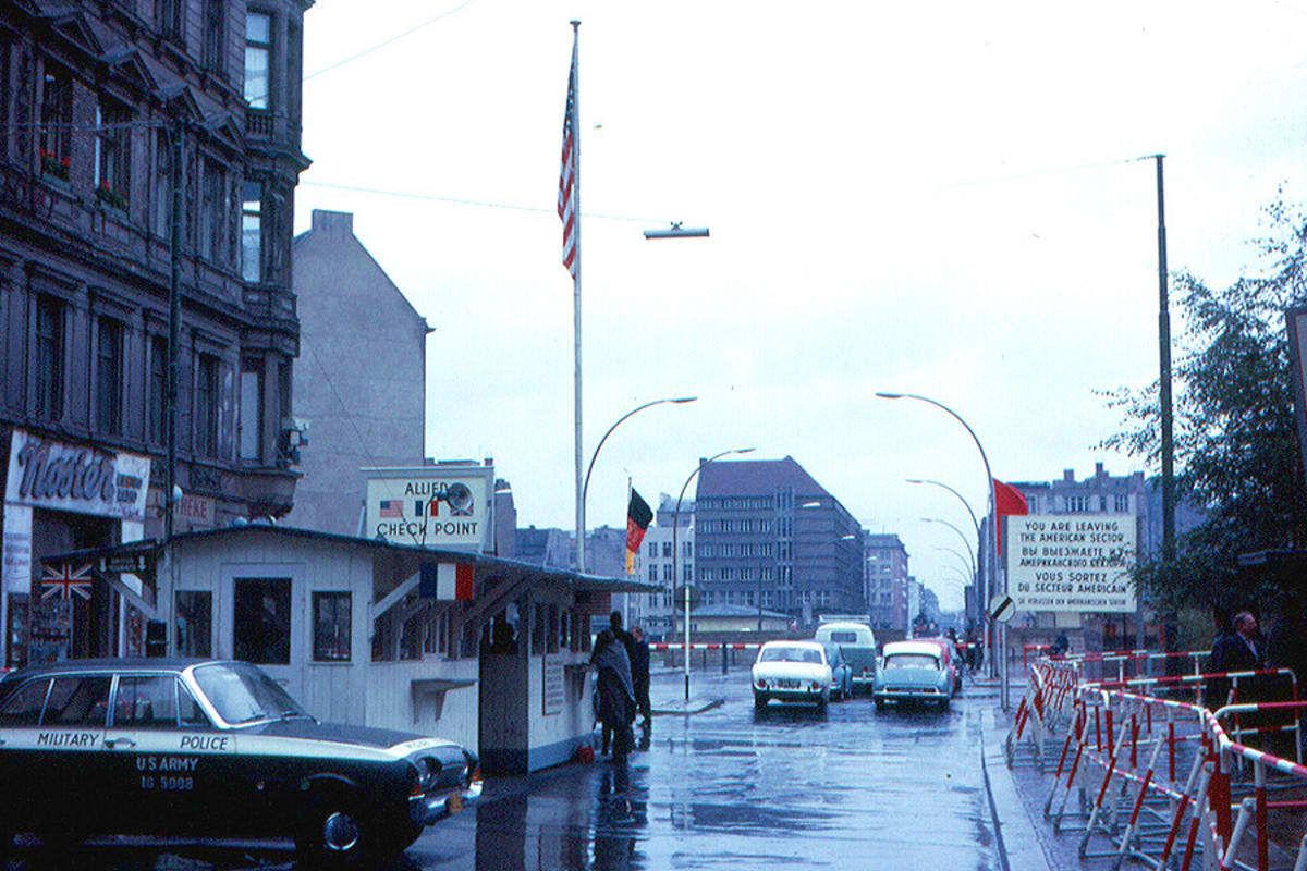 Fast Entry Berlin Wall Museum Checkpoint Charlie Tour Checkpoint Charlie guard post with American and German flags, military police car, and wet street during Cold War era Berlin