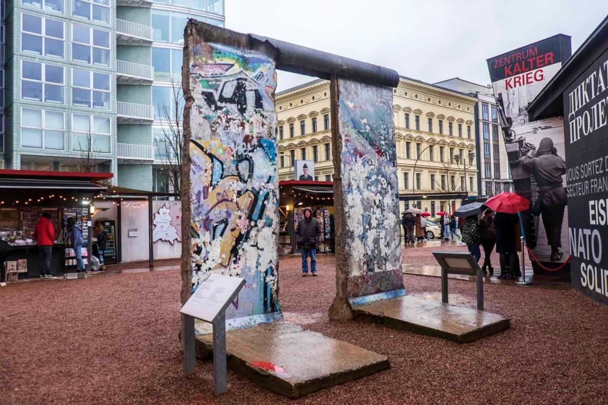 Fast Entry Berlin Wall Museum Checkpoint Charlie Tour Remaining sections of the Berlin Wall with colorful graffiti and street art displayed in an urban plaza with historic buildin