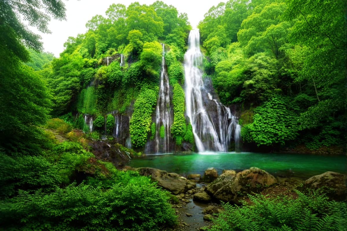 Bali Private Full Day Temple And Waterfall Tour Tropical waterfall cascading into emerald pool surrounded by lush green forest vegetation and moss-covered rocks