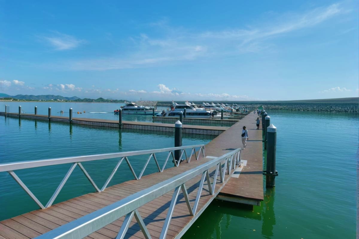 Nusa Penida Day Tour Meet at Sanur Harbor Wooden pier with white railings at Sanur Harbor in Bali, with moored boats and turquoise water