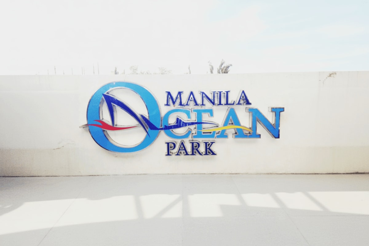 Manila Ocean Park Manila Ocean Park sign on white wall with blue logo and sailing ship design