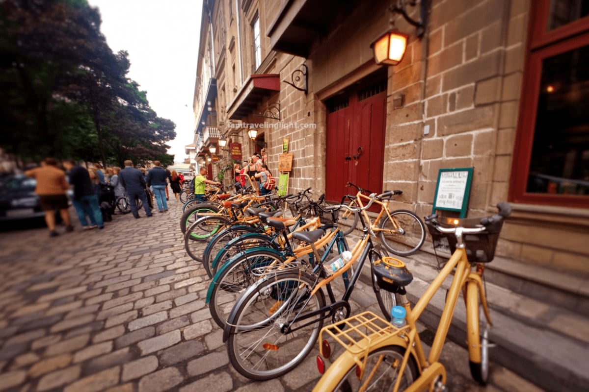 Intramuros Bambike Tour Row of yellow bamboo bikes parked on cobblestone street in historic Intramuros with colonial stone buildings and red doors