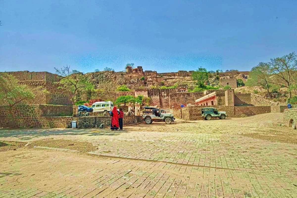 Ancient stone fort village with traditional architecture, local vehicles, and inhabitants in traditional red clothing near Ra