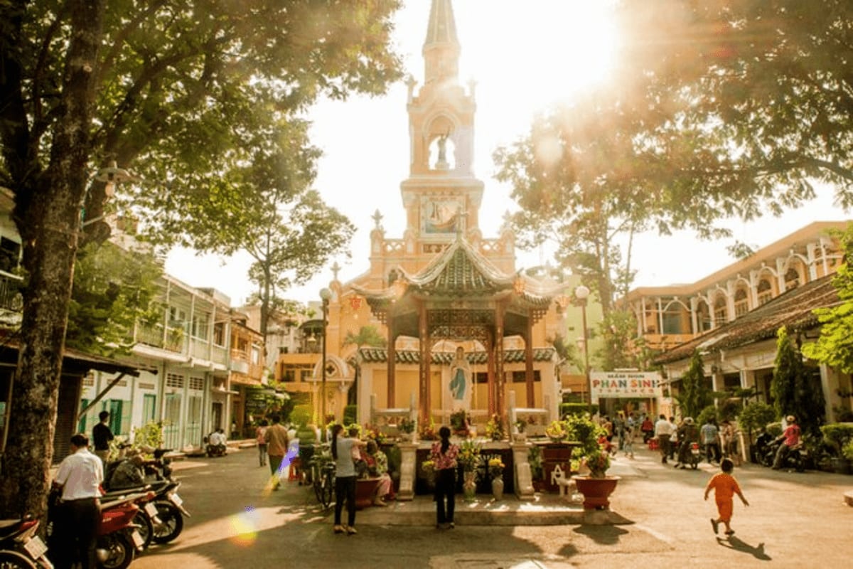 Ho Chi Minh Full day Private Tour Historic Ho Chi Minh City church with yellow colonial architecture, clock tower, and courtyard filled with visitors and motor