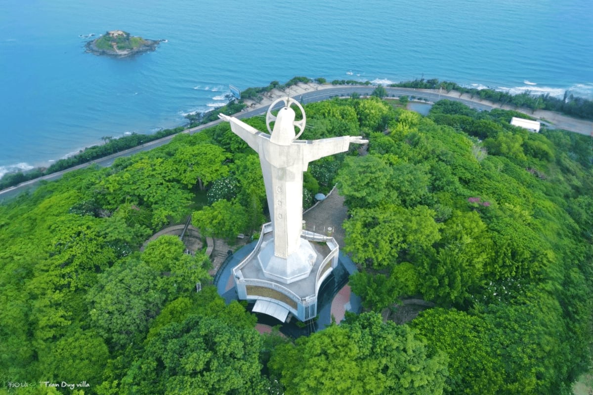 Vung Tau beach Private Tour Full Day Aerial view of giant white statue with outstretched arms on forested hilltop overlooking Vung Tau beach and coastline with tu