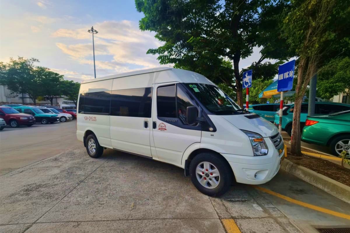 White passenger van parked in Hanoi lot with handicap parking sign, used for private airport transfers