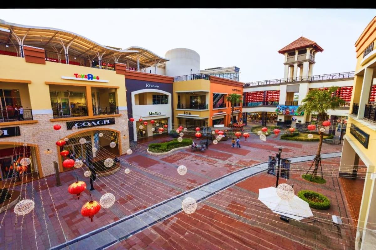 Genting Highlands Tour with Awana Cable Car and Batu Caves Visit Outdoor shopping mall courtyard with red lantern decorations, colorful storefronts including Toys R Us and Coach, brick pavin