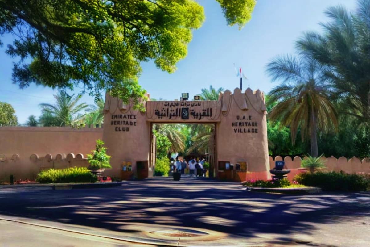 Entrance gate to UAE Heritage Village in Abu Dhabi with traditional mud-brick architecture and palm trees