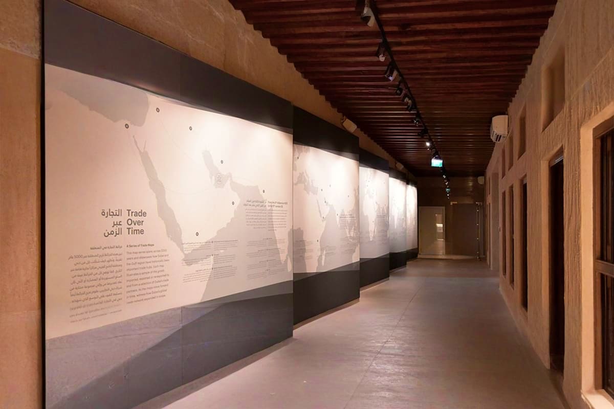 Al Shindagha Museum Museum corridor with illuminated wall panels displaying "Trade Over Time" exhibit with Arabic and English text and historical