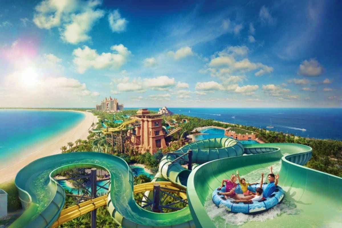 Aerial view of Atlantis Aquaventure Waterpark with green water slides, turquoise pools, beachfront, and Atlantis Hotel in Dub
