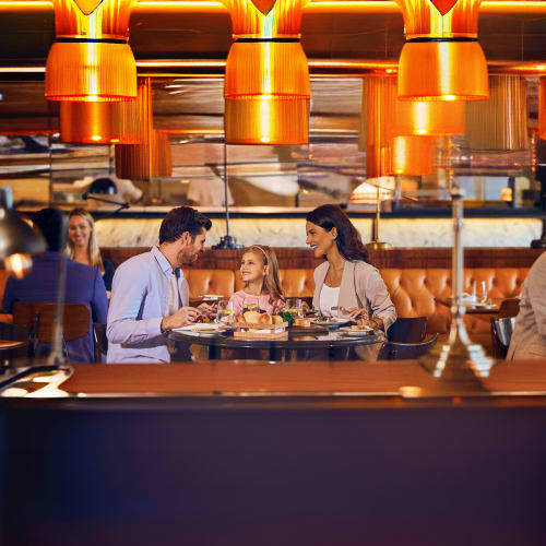Family dining at modern restaurant with orange pendant lights and leather seating at Atlantis