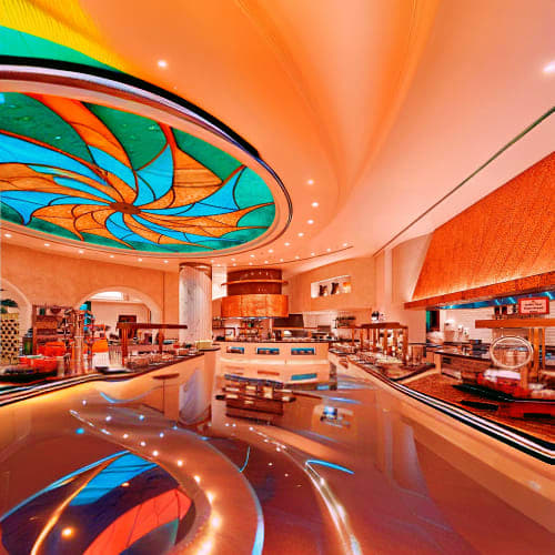 Modern restaurant interior with orange and turquoise ceiling design, reflective polished floor, and contemporary dining space