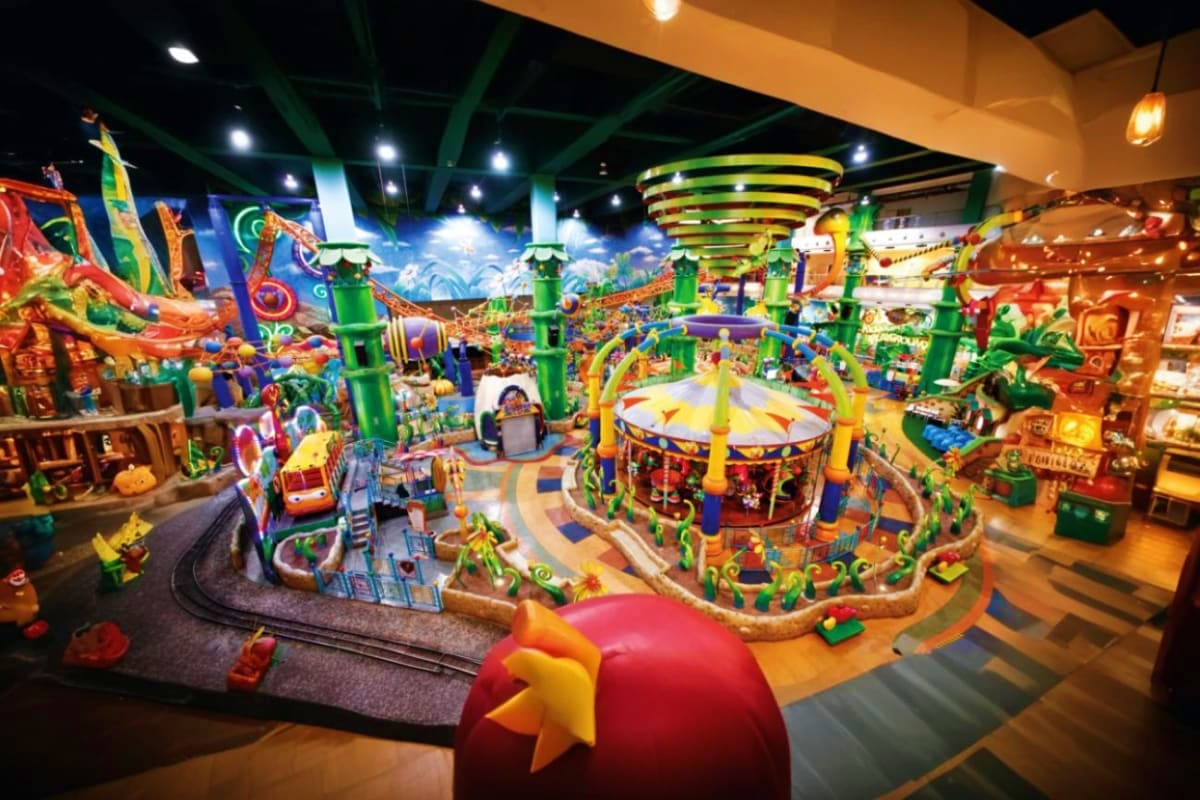 Colorful indoor amusement park at Berjaya Times Square with carnival rides, green pillars, and festive decorations under brig