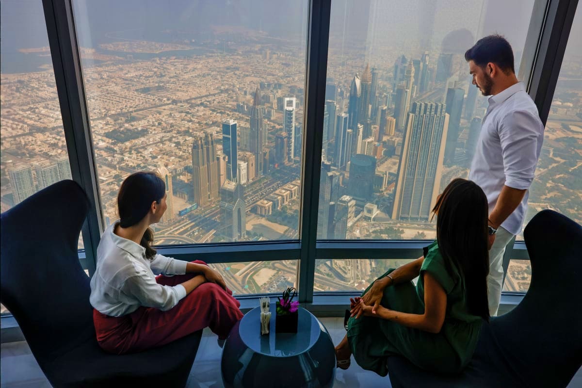 Business professionals viewing Dubai skyline and cityscape from high-rise window at Burj Khalifa observation deck