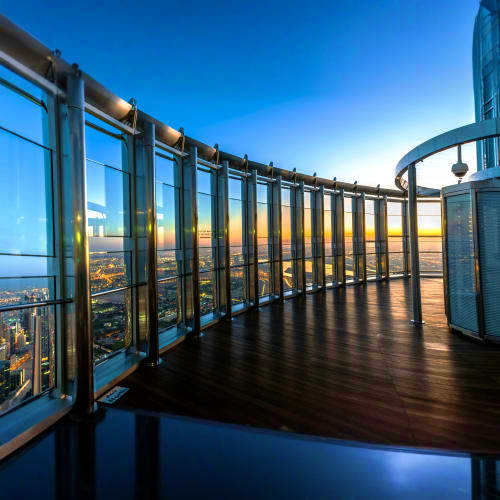 High-altitude observation deck at Burj Khalifa with floor-to-ceiling windows overlooking expansive cityscape at sunset