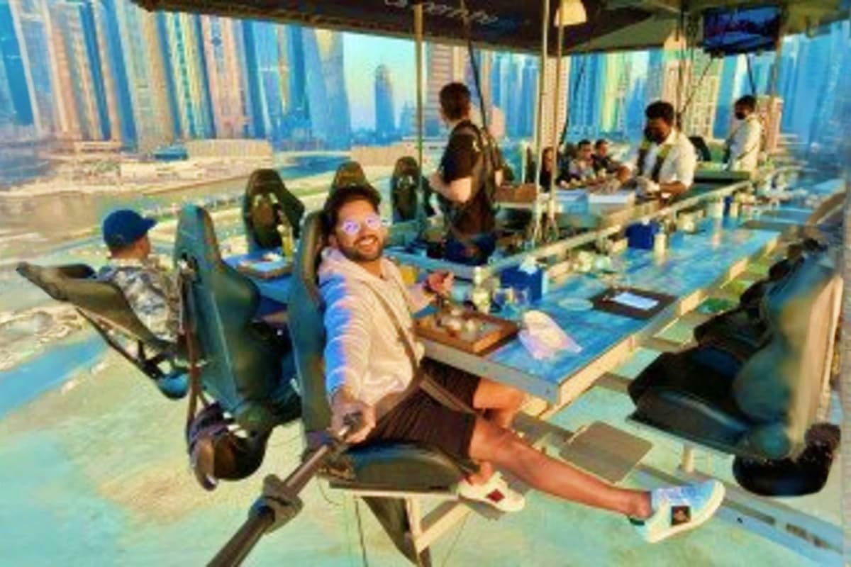People dining at suspended table high above city skyline with skyscrapers visible in background during Dinner in the Sky expe