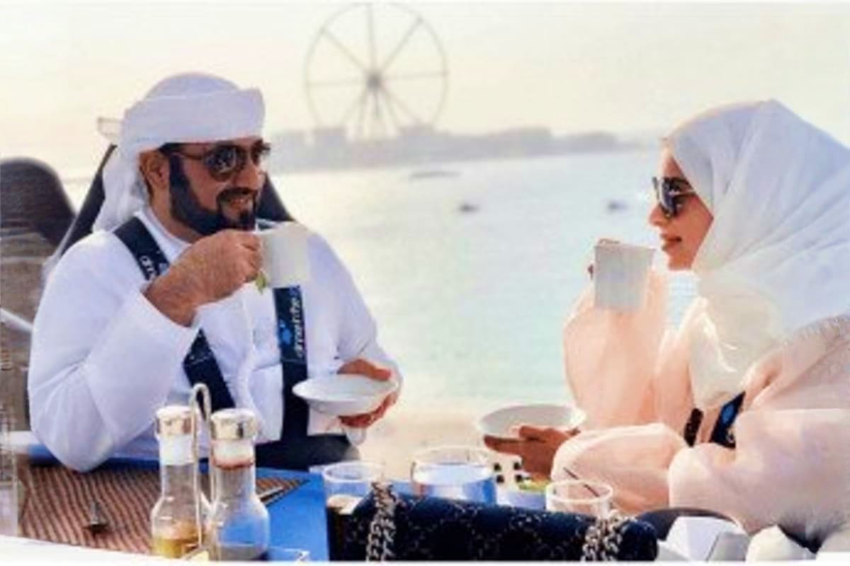 Two people dining outdoors with a Ferris wheel visible in the background over water