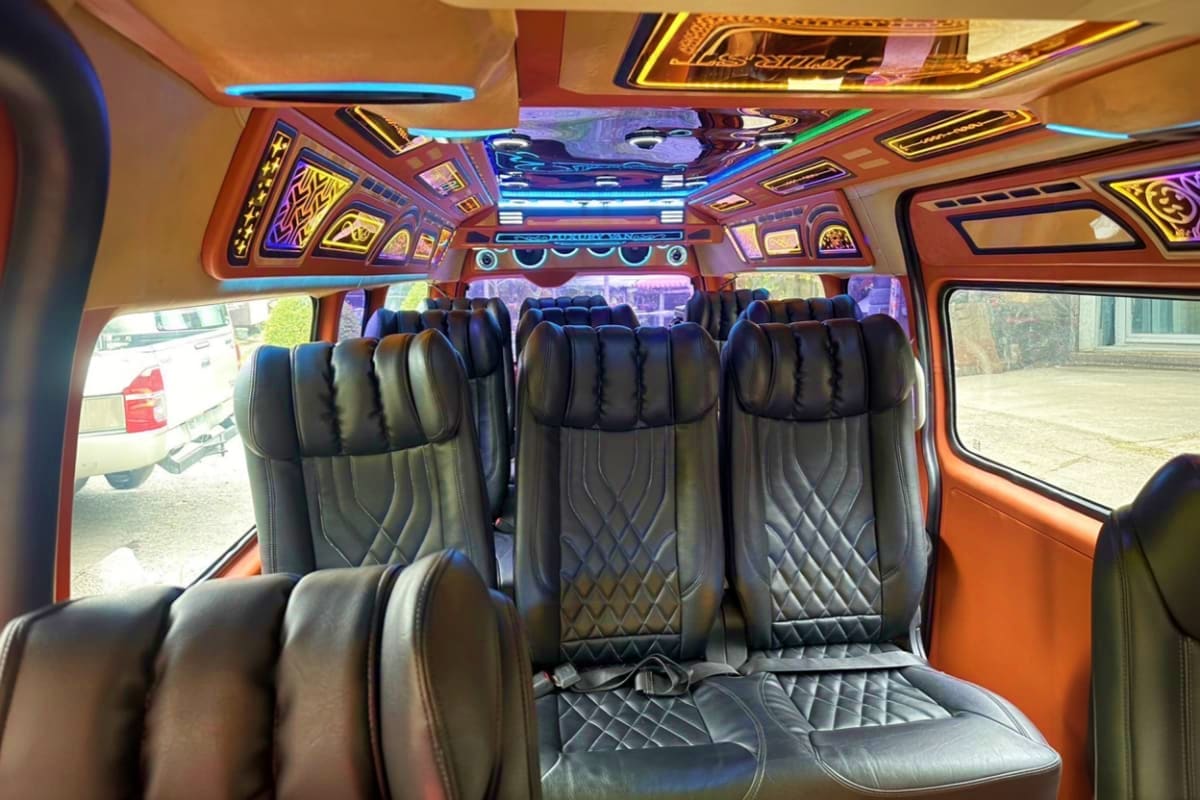 Donmueang International Airport Pickup Luxury tour bus interior with quilted black leather seats, decorative ceiling panels with blue neon lighting, and windows sho