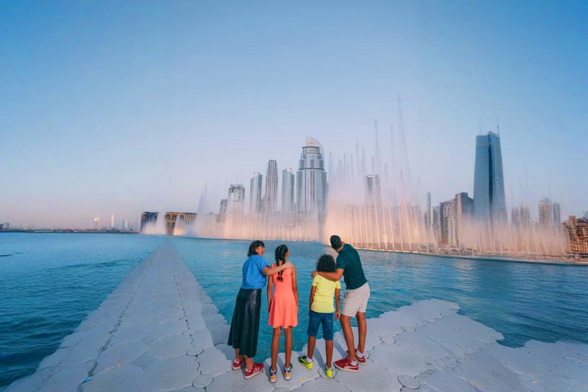 Dubai Fountain Show and Lake Ride Family of four watching Dubai Fountain show from pier, with illuminated fountain jets and skyline in background