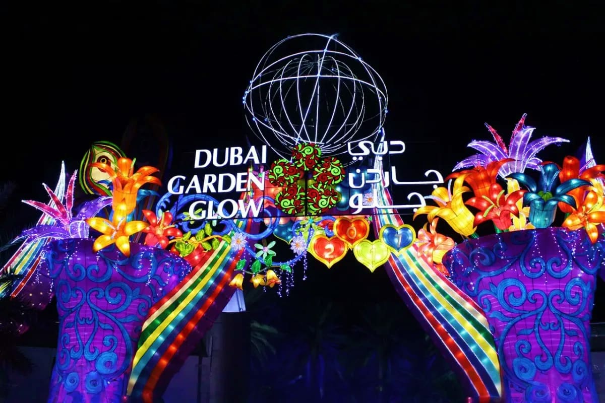Illuminated Dubai Garden Glow entrance display with glowing flower sculptures and ornamental globe structure at night