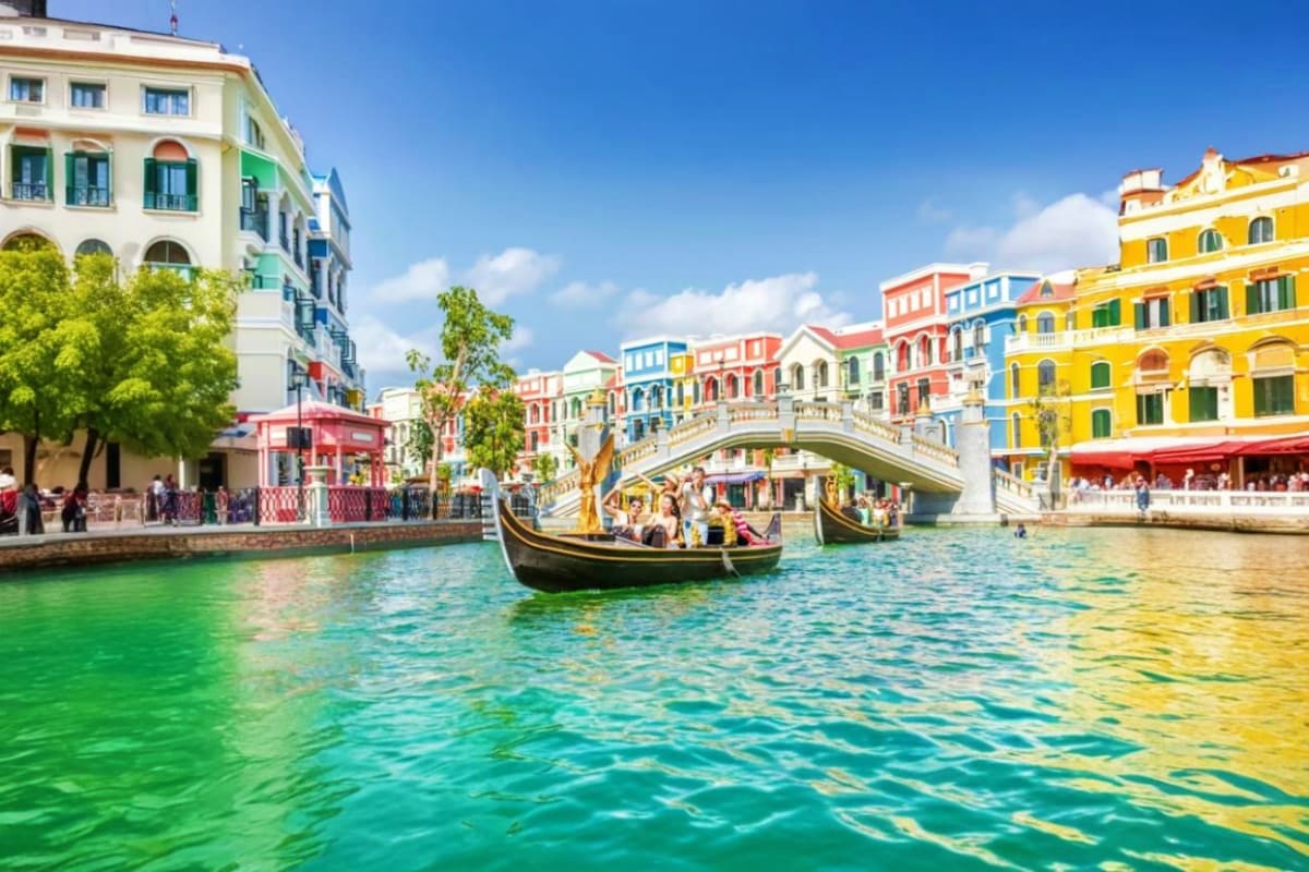 Grand World with Gondola Ride Gondola boat traveling through a Venice-themed canal with colorful buildings and arched bridge in Grand World theme park