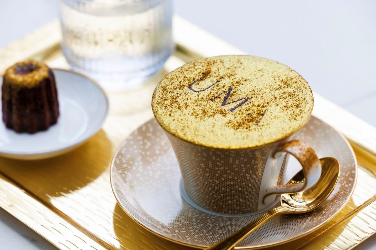 Guided Inside Burj Al Arab Tour Luxury dessert presentation at Burj Al Arab featuring gold-dusted soufflé in textured cup with gold spoon and fine dining tab